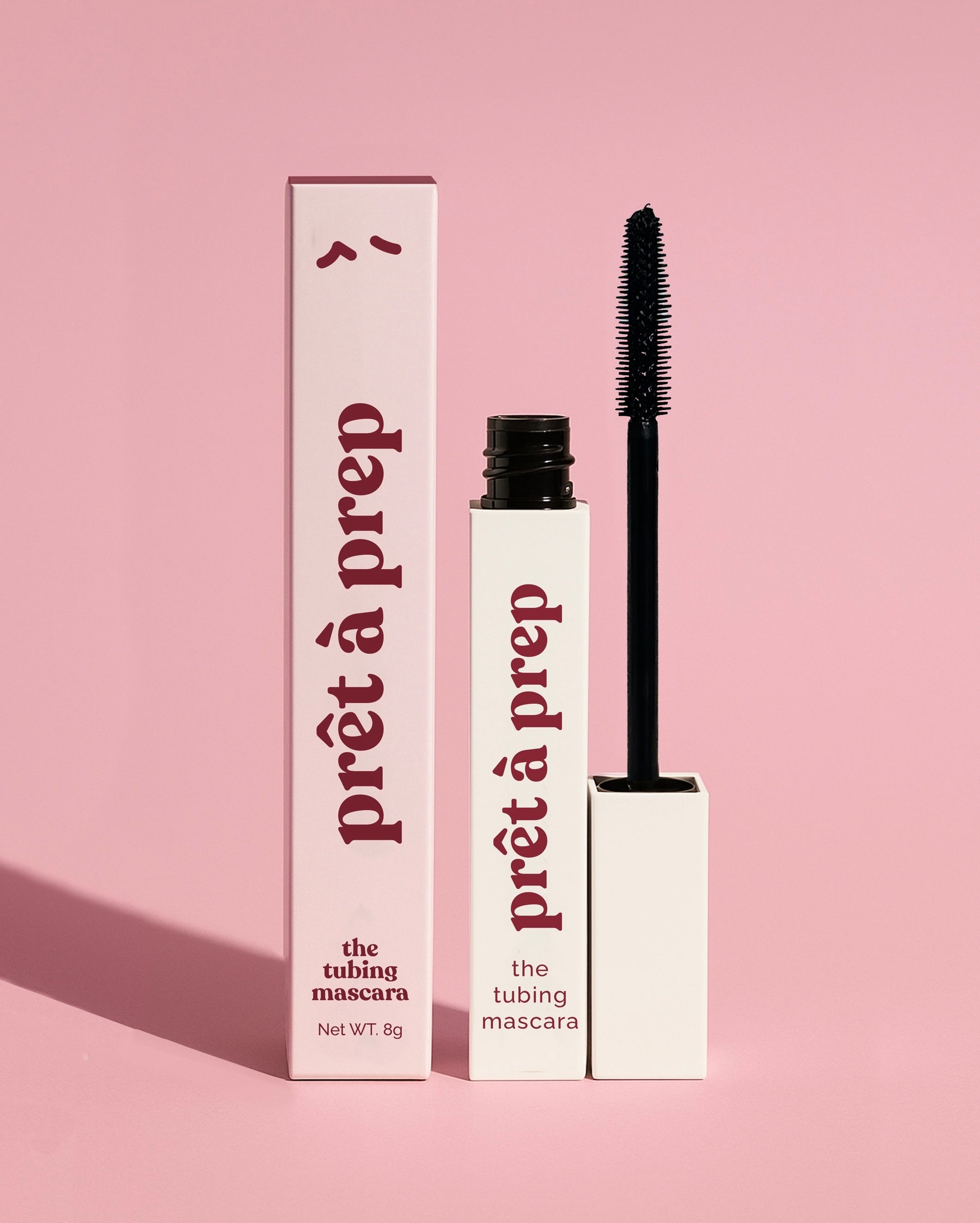 White mascara bottle and pink mascara box with Pret a prep logo printed on a pink background consistent