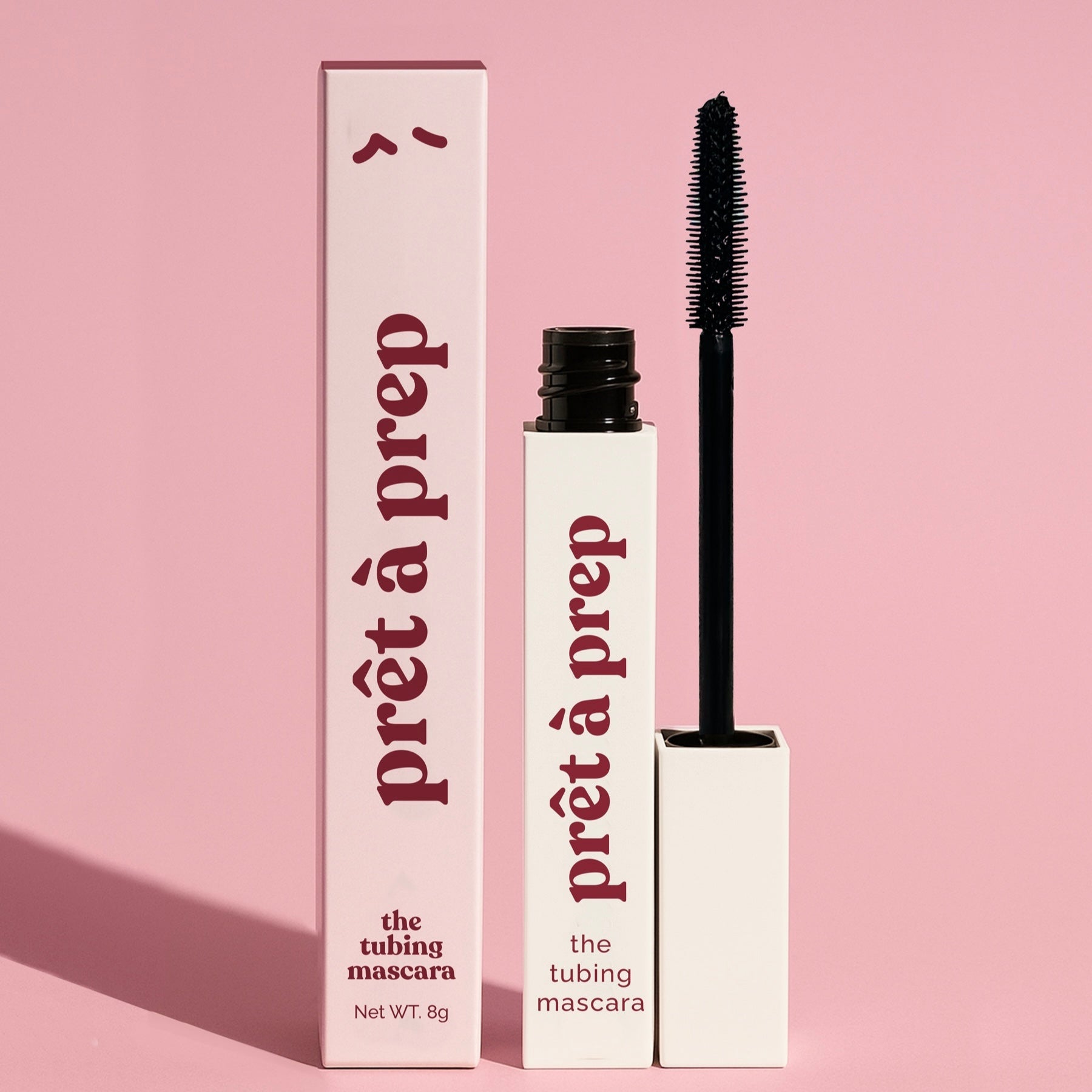 White mascara bottle and pink mascara box with Pret a prep logo printed on a pink background consistent