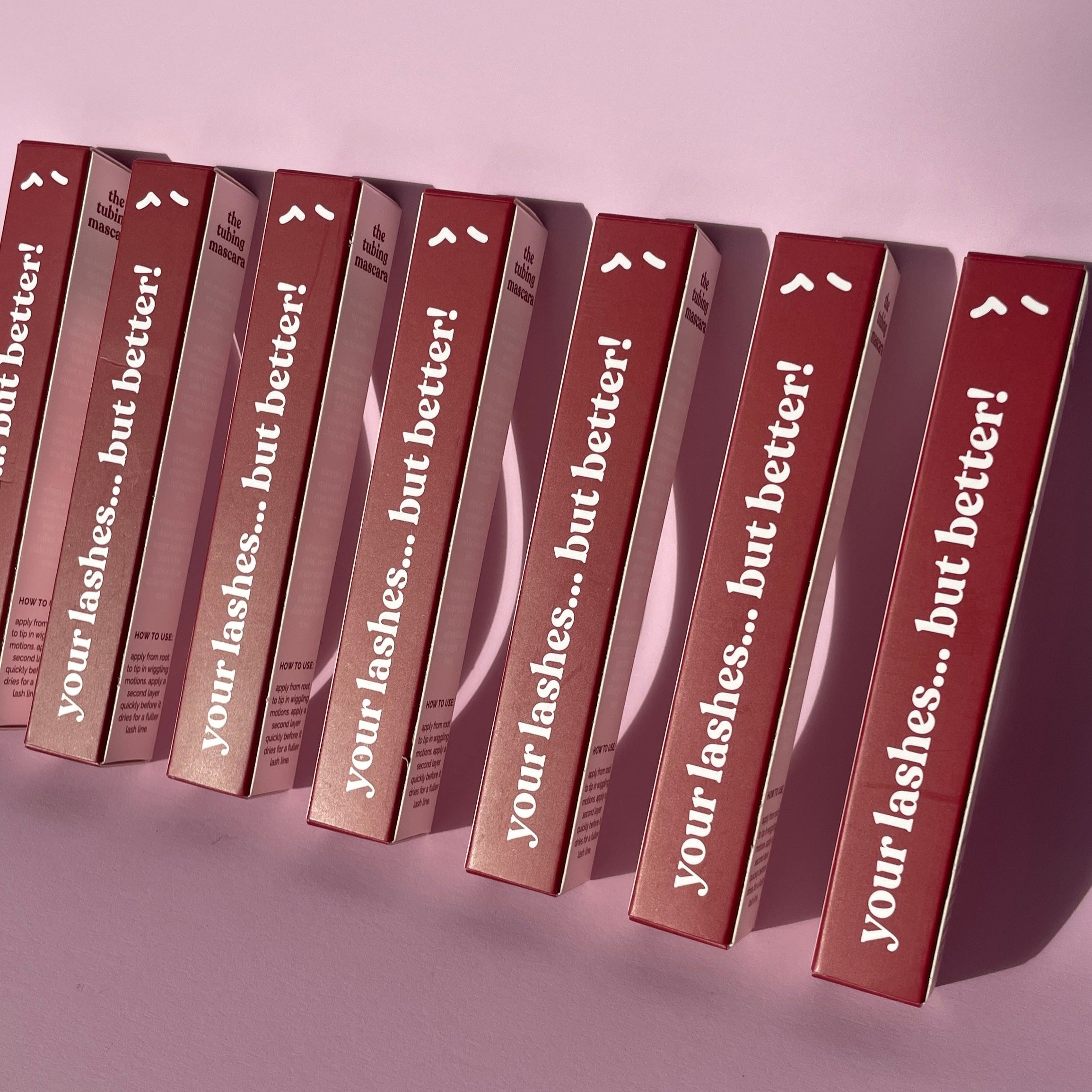 Multiple boxes of eyelash product with 'your lashes... but better!' text on a pink background
